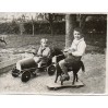 Chłopcy ze swoimi zabawkami: blaszanym samochodzikiem i koniem na podeście z kółeczkami