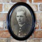 Duża fotografia z portretem jasnowłosego polskiego oficera w owalnej drewnianej ramie