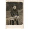 Kobieta z książką stojąca przy drewnianym, stylizowanym meblu na pamiątkowej fotografii