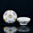 Kremowa porcelana z wielobarwnymi kompozycjami kwiatowymi przeplatanymi złotymi ornamentami floralnymi