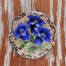 Porcelanowa brosza zdobiona niebieskimi kwiatami goryczki. 