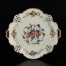 Kwietne bukiety i złote ornamenty na porcelanie barwy kości słoniowej. 