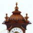 Zbliżenie na ozdobną koronę zegara z niewielkimi ubytkami w drewnie na listewce